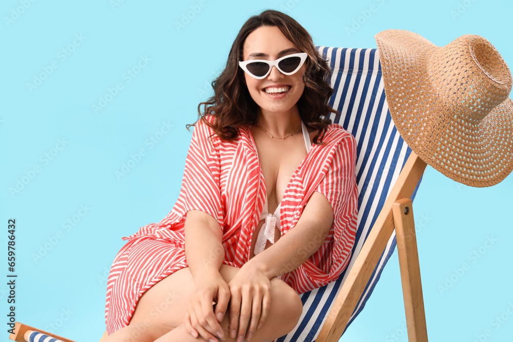 Young woman in deck chair on blue background