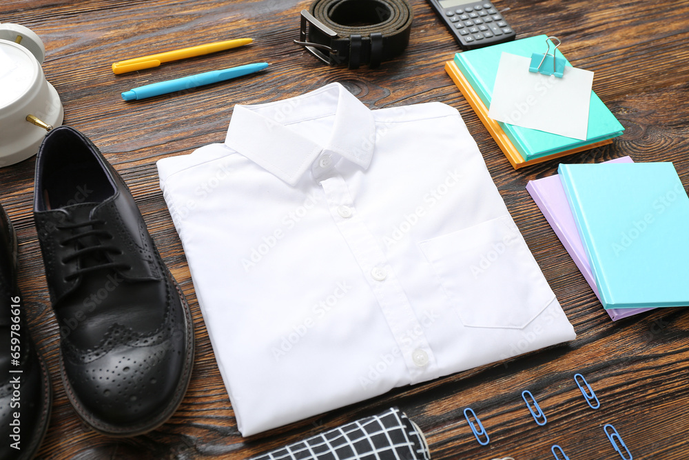 Different stationery with stylish school uniform on brown wooden background