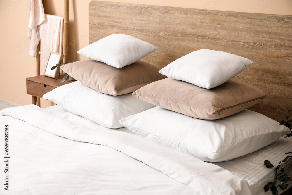 Comfortable bed with stacked pillows in bedroom, closeup