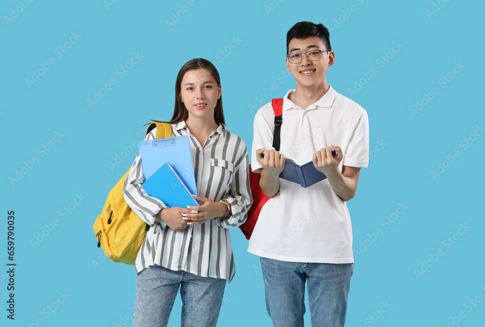 Happy students with backpacks and books on blue background