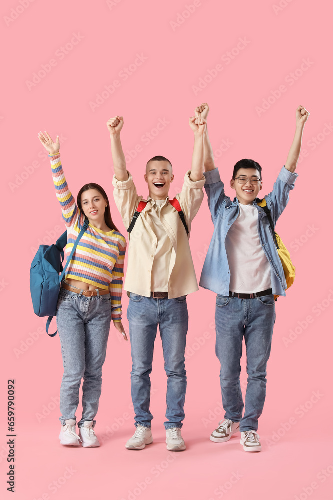 Happy students with backpacks on pink background