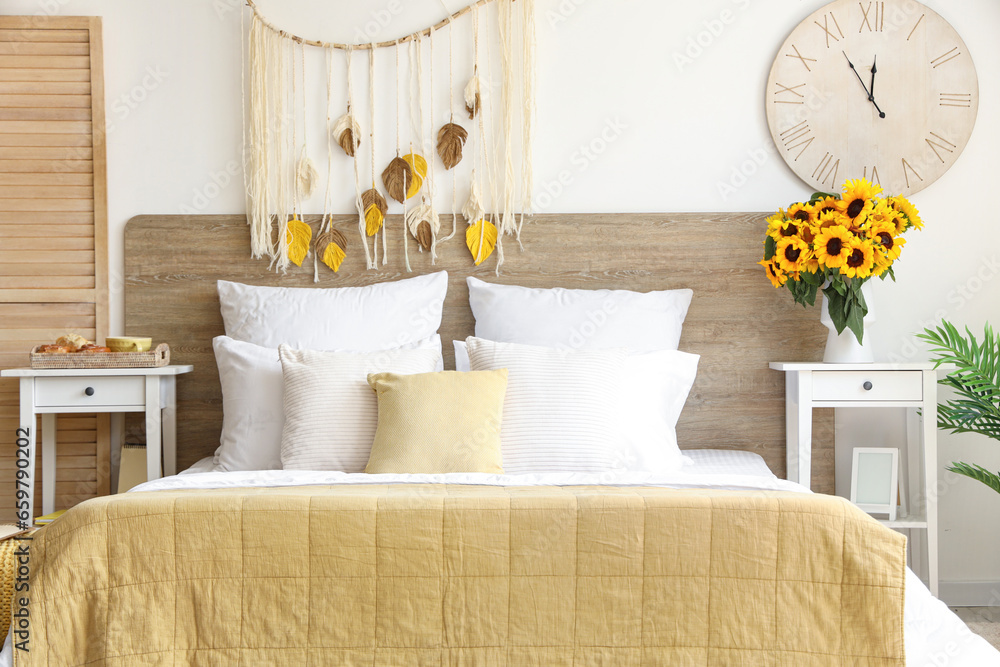 Interior of light bedroom with sunflowers in vase on table