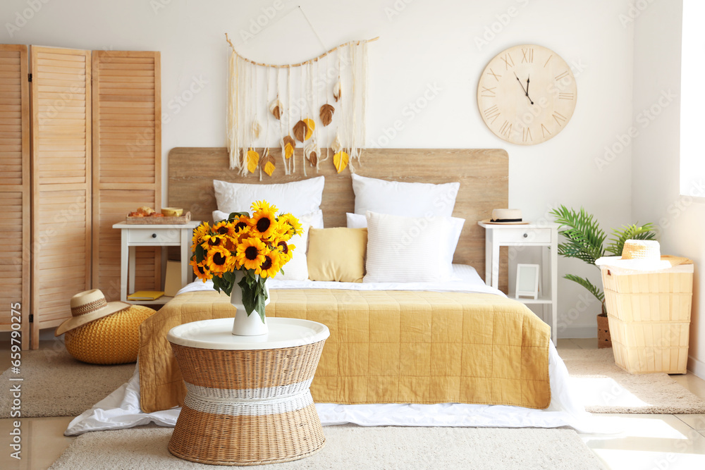 Interior of light bedroom with sunflowers in vase on table