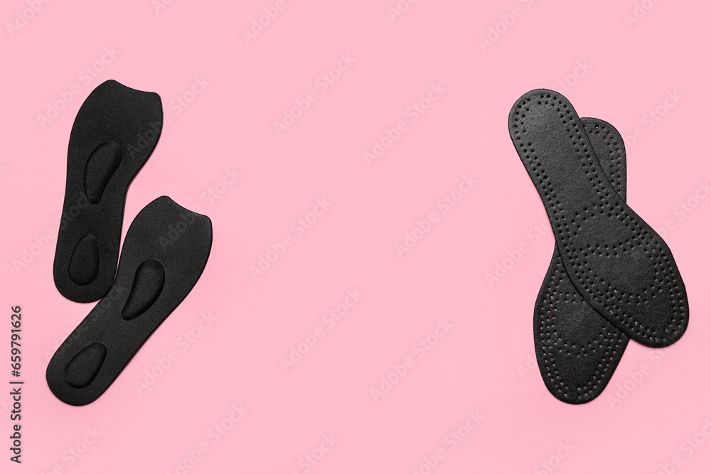 Black orthopedic insoles on pink background