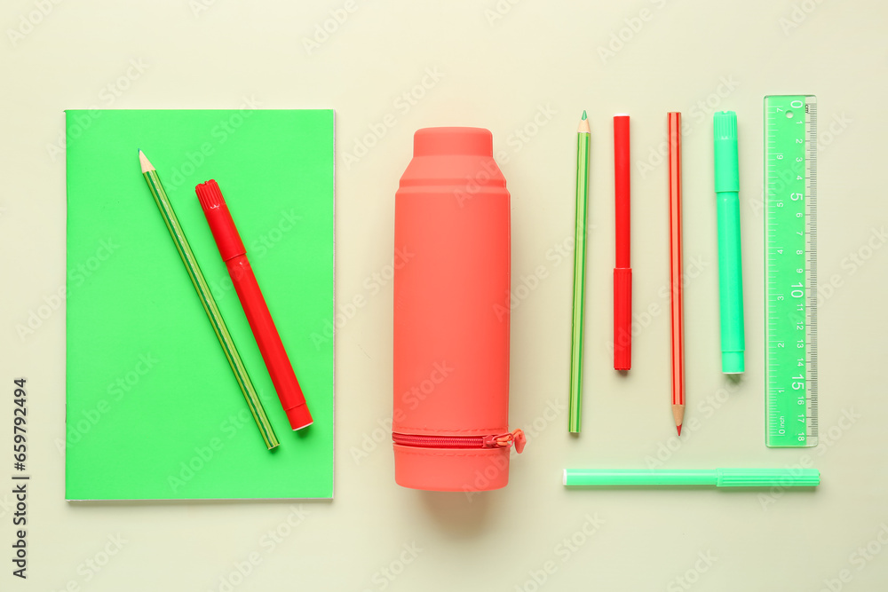 Red pencil case with school stationery on green background