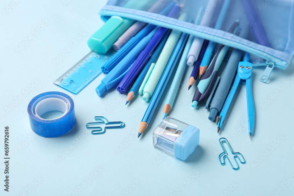 Pencil case with school stationery on blue background, closeup