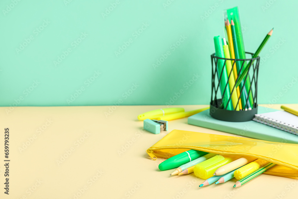 Yellow pencil case with school stationery on color background