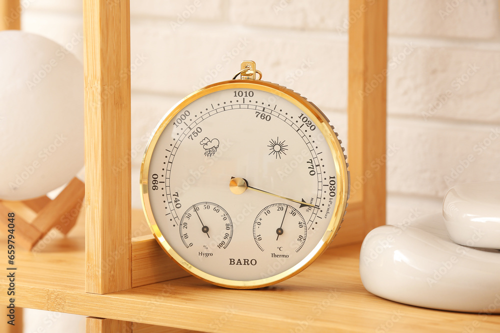 Aneroid barometer and decor on shelving unit in room, closeup