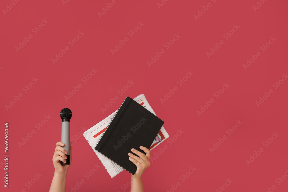 Female hands with notebook, newspaper and microphone on color background