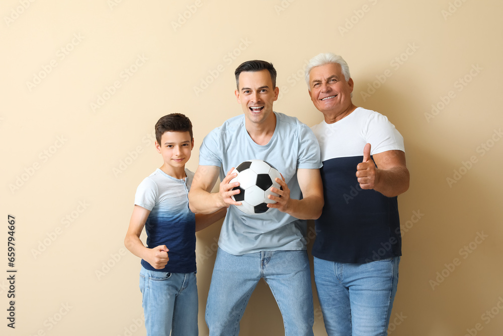 Little boy with his dad and grandfather holding soccer ball on beige background