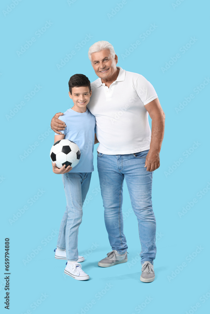 Little boy with his grandfather and soccer ball on blue background