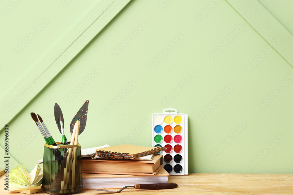 Holder with different painters supplies on wooden desk