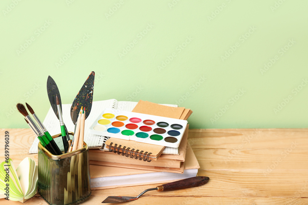 Holder with different painters supplies on wooden desk