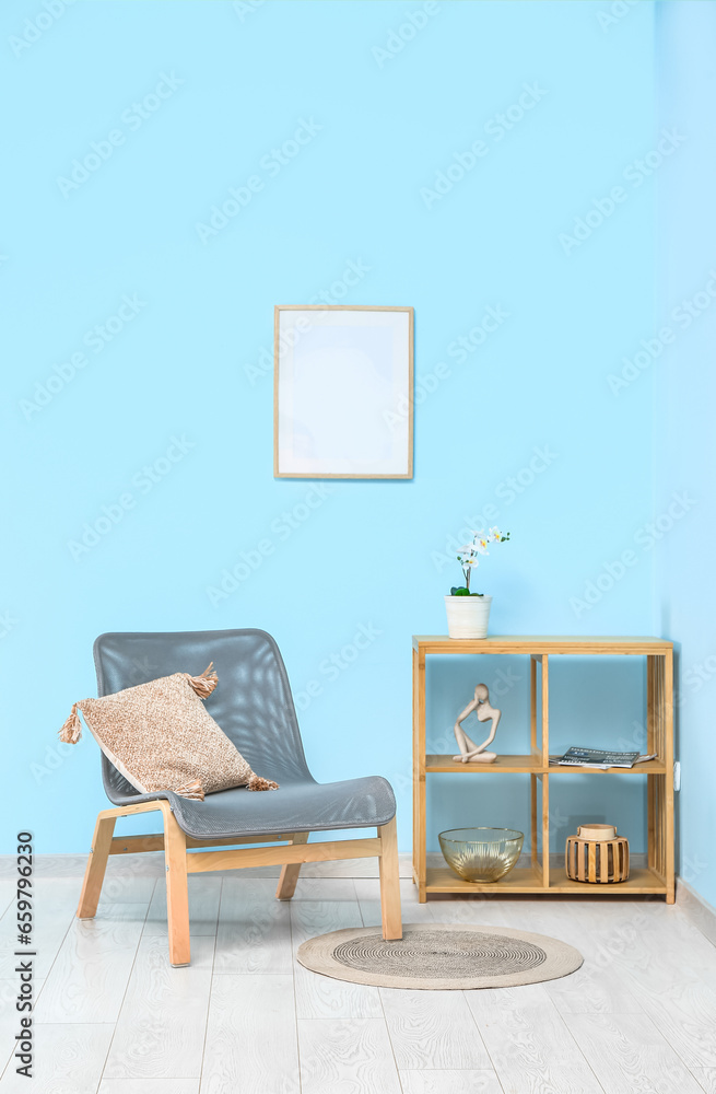 Comfortable armchair and shelving unit with decor near color wall