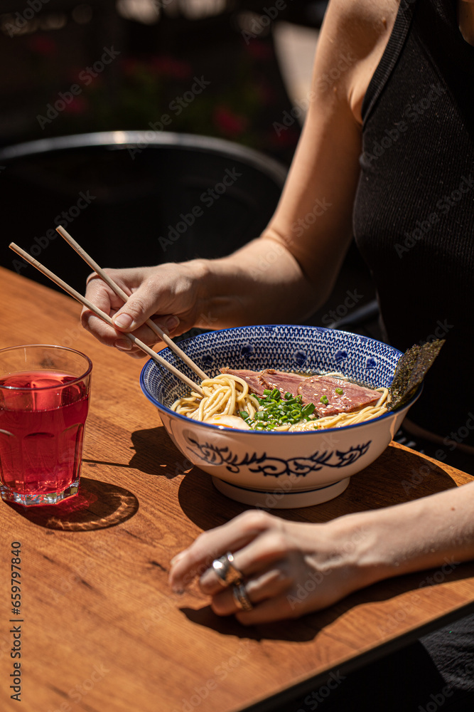 Woman eating japanese ramen noodle soup with pastrami