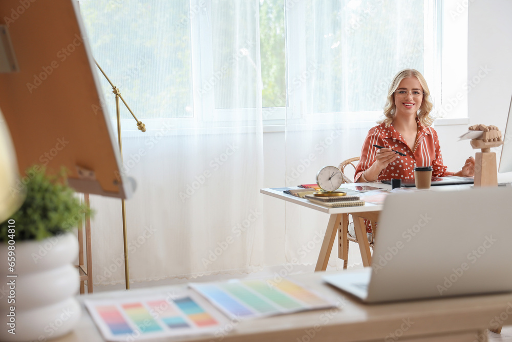 Female interior designer working with graphic tablet at table in office