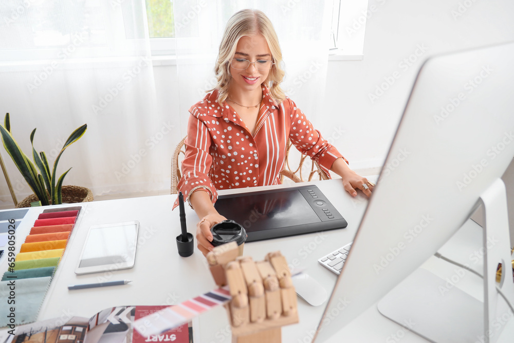 Female interior designer working with graphic tablet at table in office