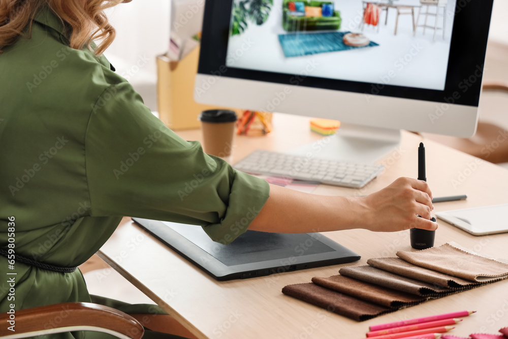 Female interior designer working with graphic tablet at table in office, closeup