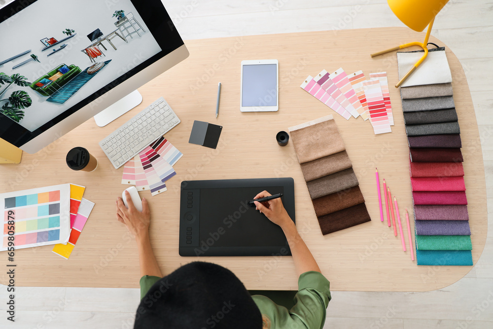 Female interior designer working with graphic tablet at table in office, top view