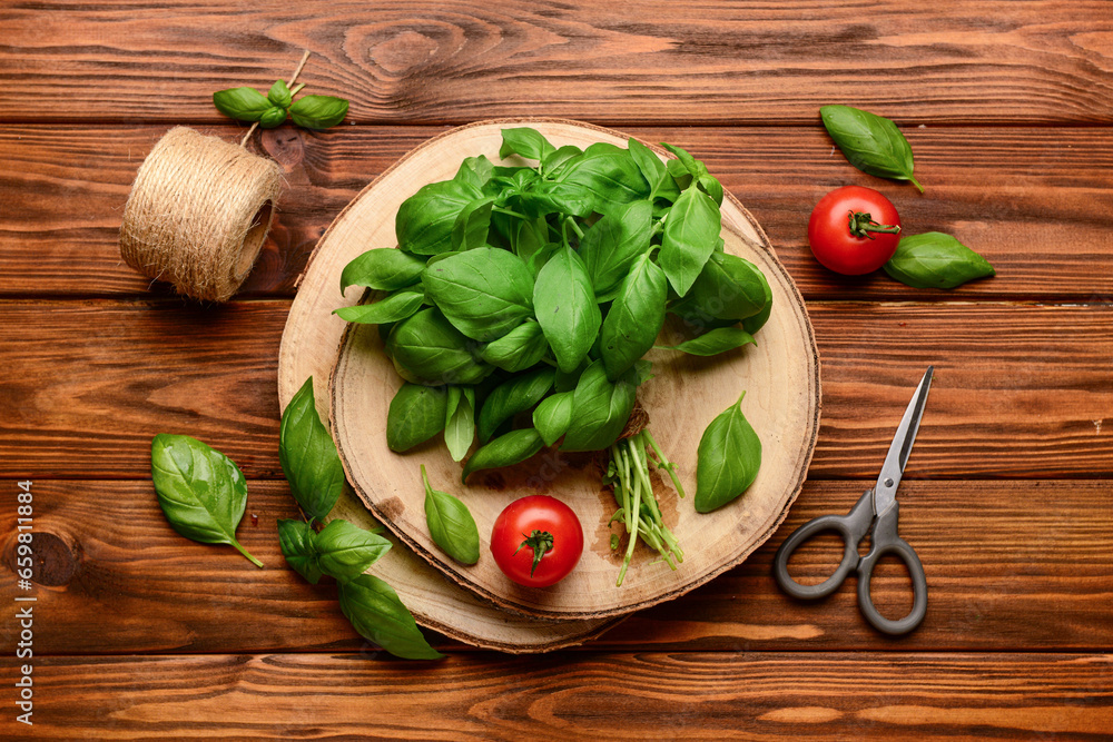 Board with fresh green basil and tomatoes on wooden background