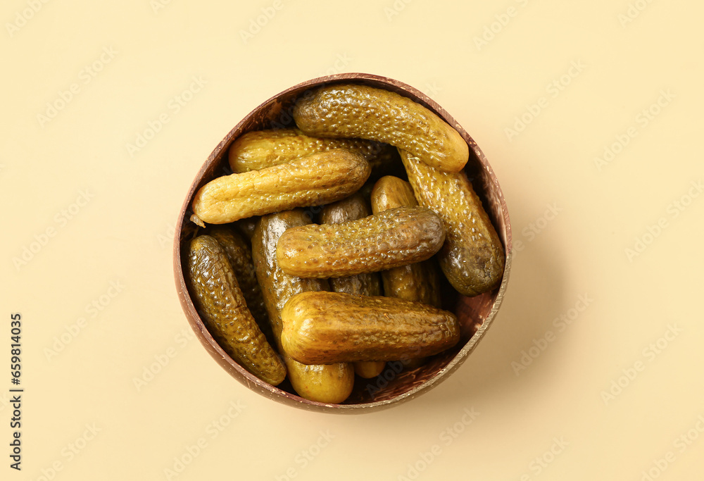 Wooden bowl with tasty pickled cucumbers on orange background