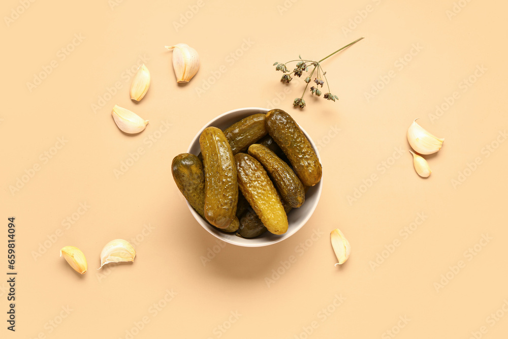 Bowl with tasty pickled cucumbers and garlic on orange background