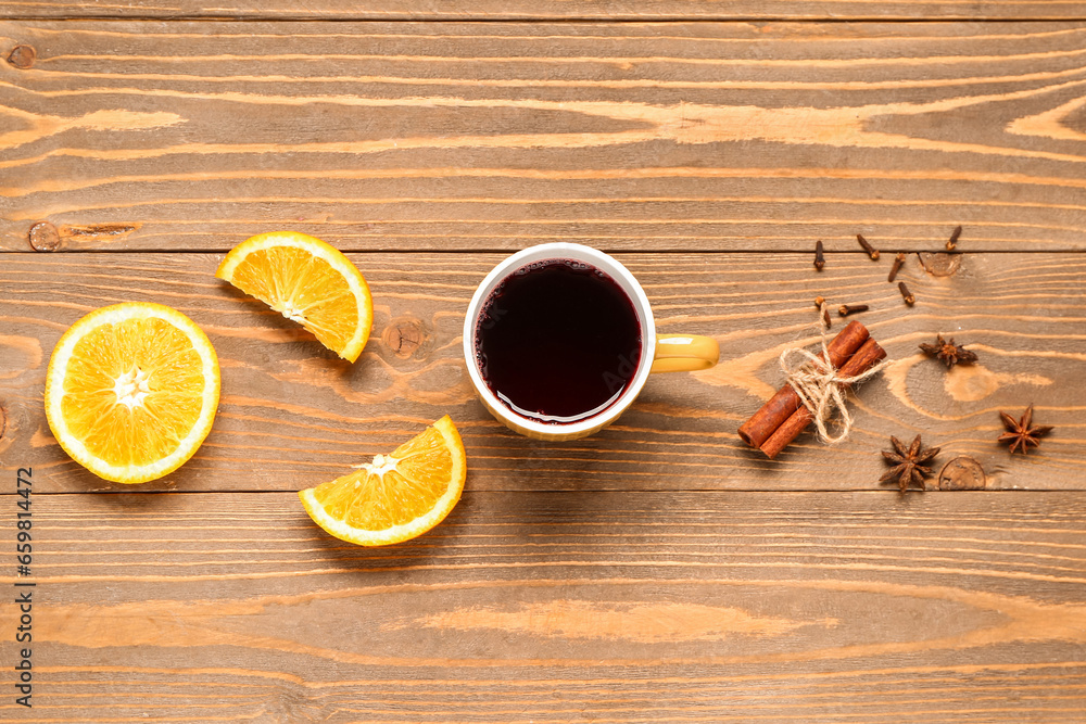 Cup of hot mulled wine and different spices on wooden background