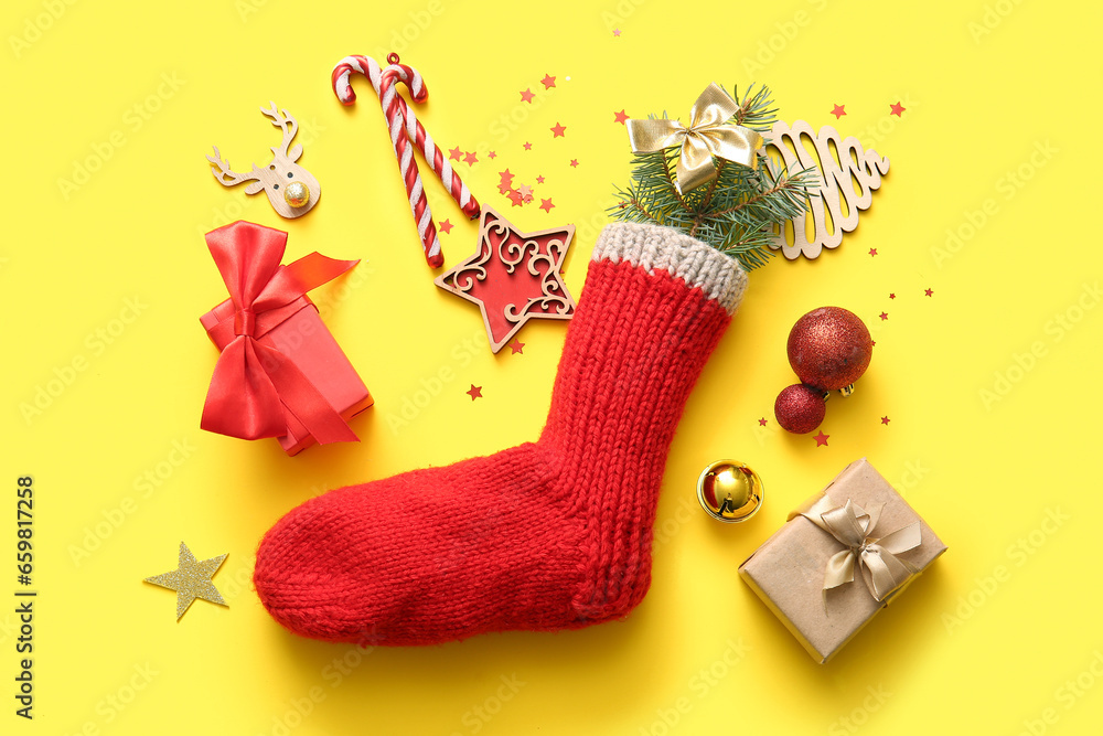 Beautiful Christmas sock with gift boxes and decorations on yellow background