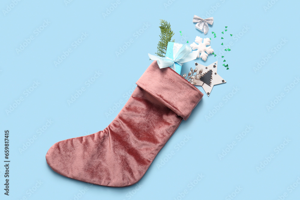 Beautiful Christmas sock with gift box and decorations on blue background