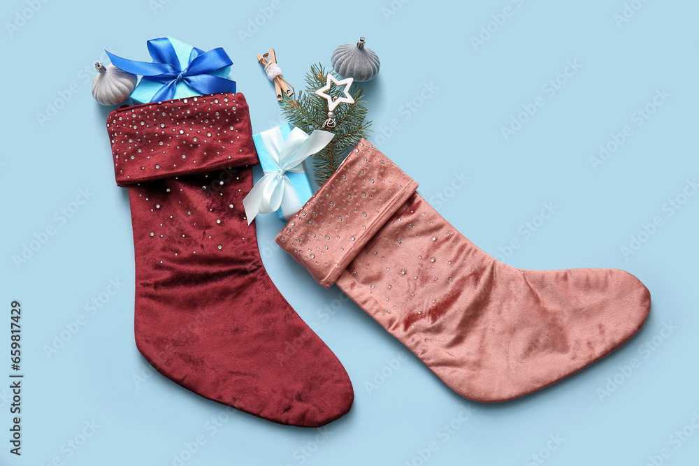 Beautiful Christmas socks with gift boxes and decorations on blue background