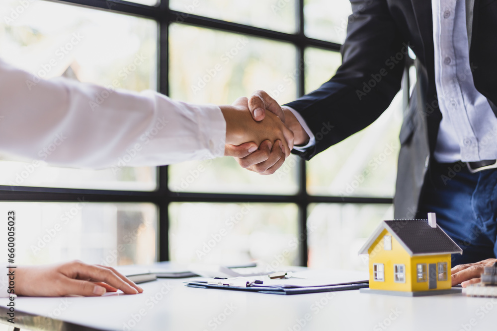 Businessman shaking hands with real estate agent in office after reaching home purchase agreement.