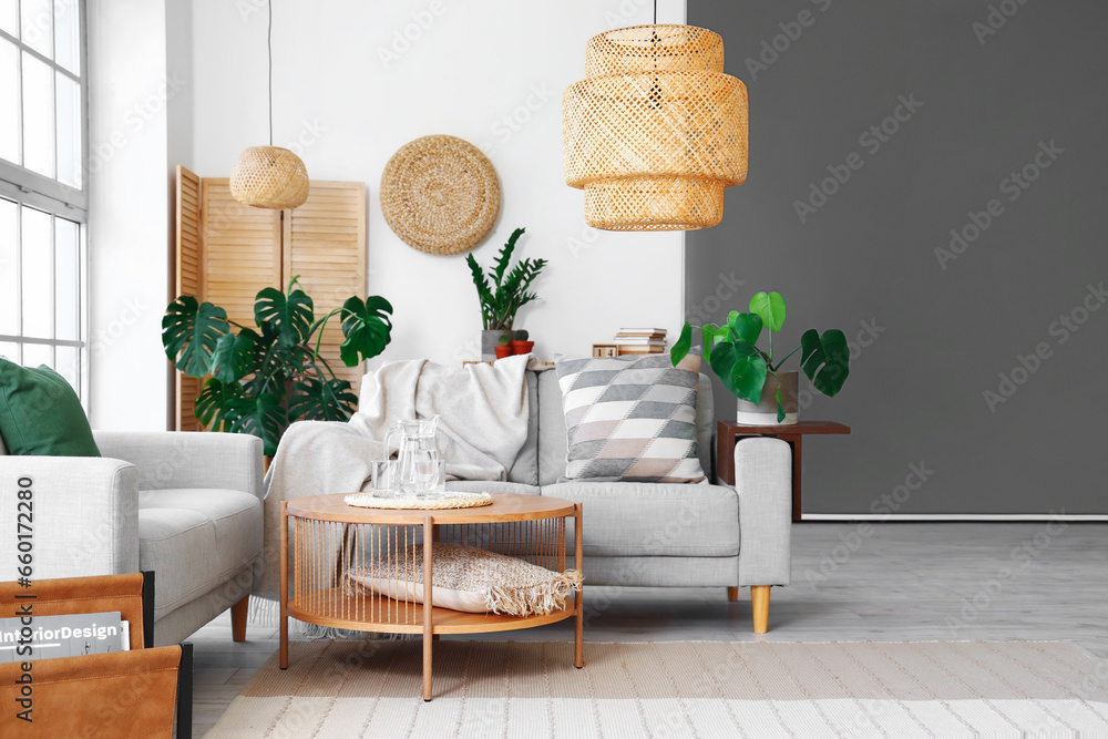 Interior of light living room with sofas and Monstera houseplant