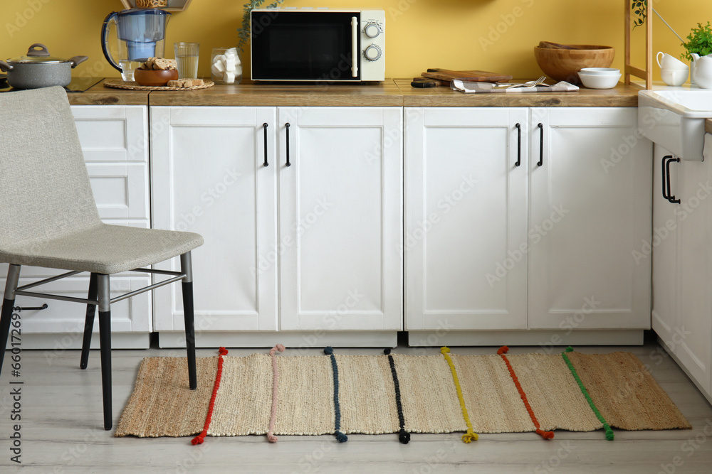 Chair and stylish rug on floor in modern kitchen