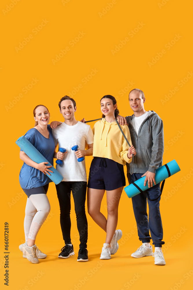 Group of sporty young people with equipment on yellow background