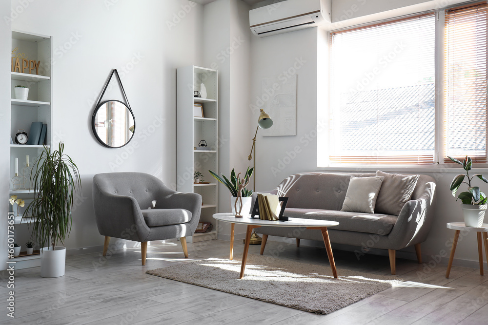 Interior of light living room with sofa, armchair and table