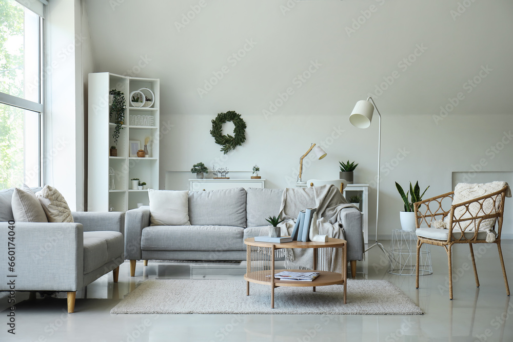 Interior of living room with sofas, armchair and stylish holder for books on coffee table