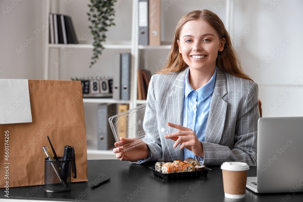 Happy young woman with sushi and paper bag in office