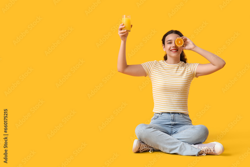 Teenage girl with glass of juice and orange sitting on yellow background