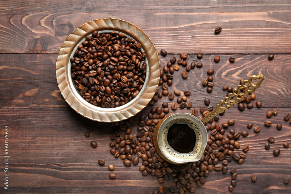 Coffee in cezve with scattered beans on brown wooden background