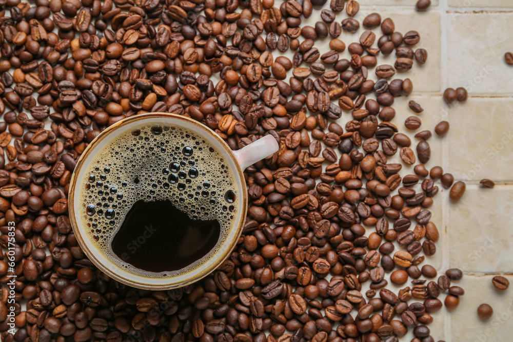 Cup of coffee and scattered beans on beige tile background