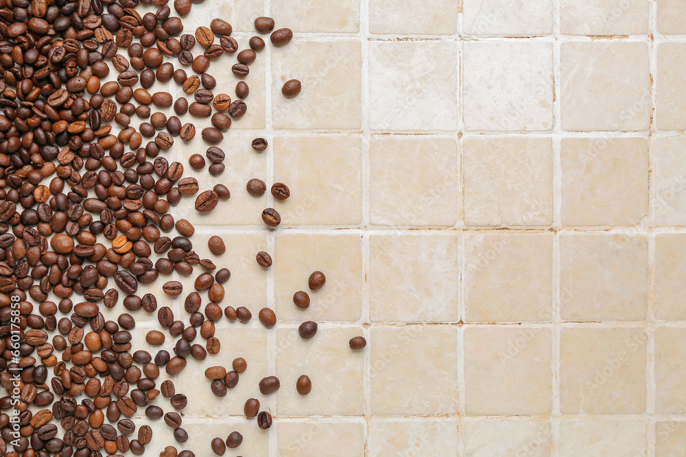 Scattered coffee beans on beige tile background