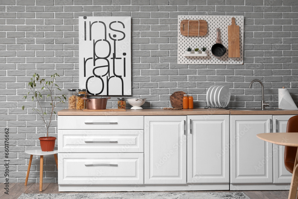 Sink, plate rack and utensils on white counters in modern kitchen