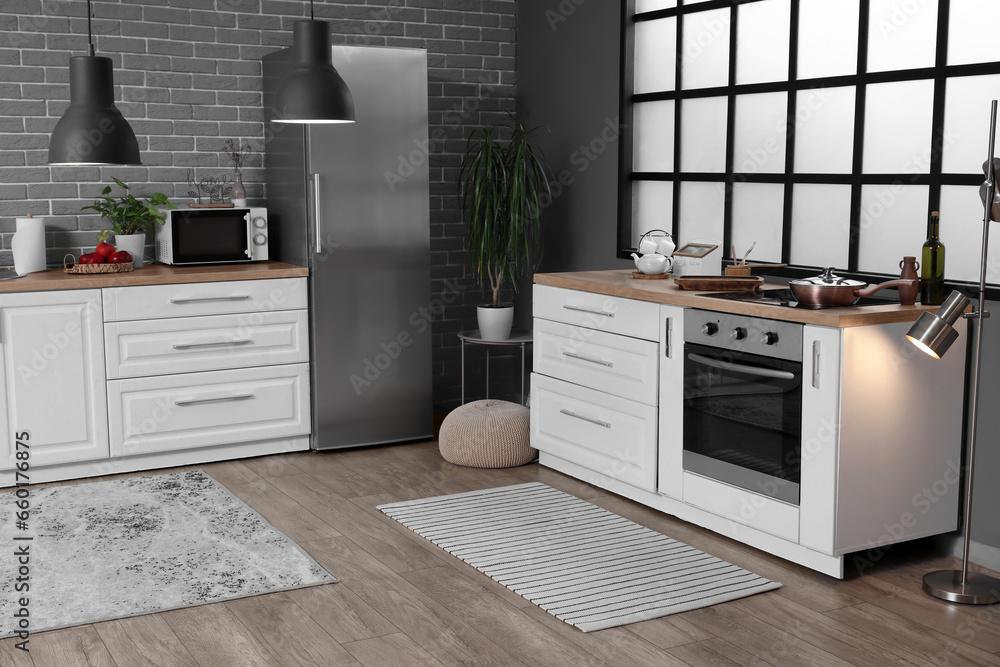 Interior of modern kitchen with white counters, fridge and electric oven