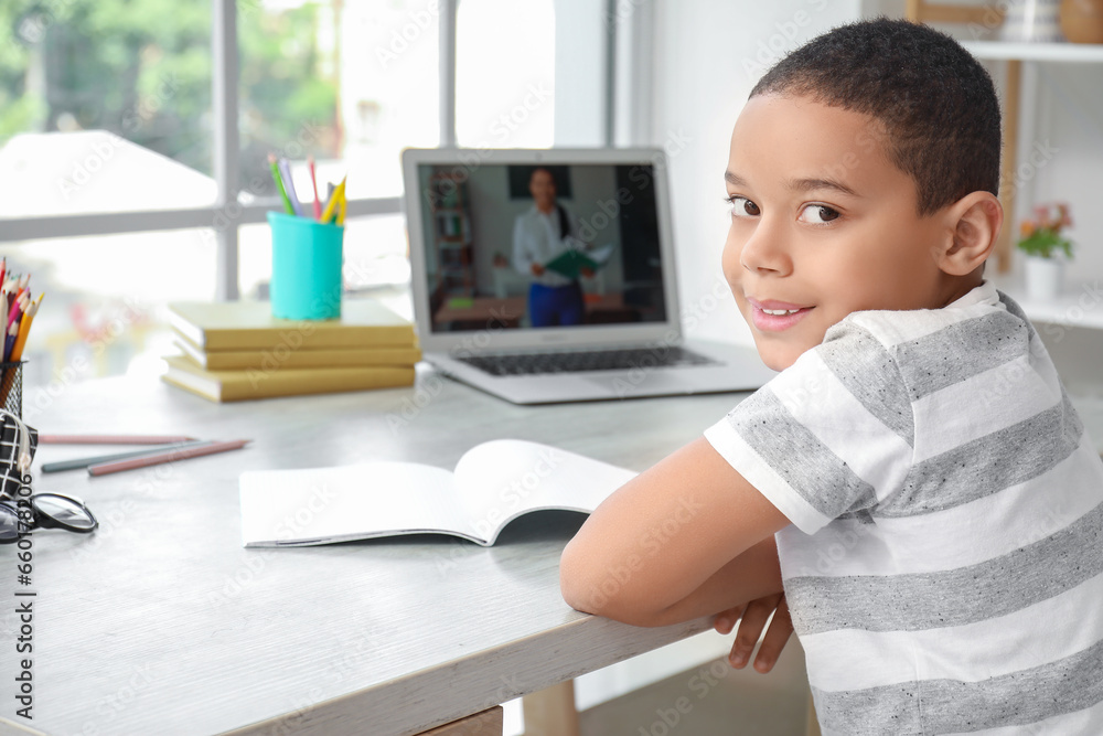 Little African-American boy studying online with laptop at home