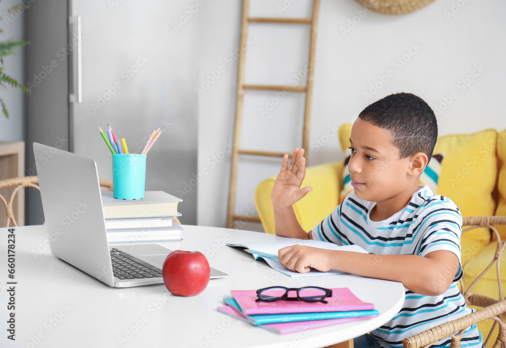 Little African-American boy studying online with laptop at home