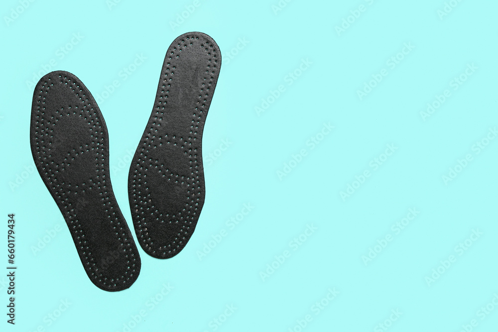 Pair of black orthopedic insoles on color background