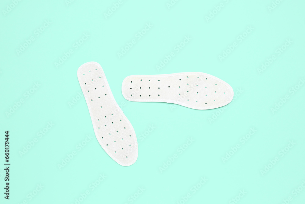 Pair of white orthopedic insoles on color background