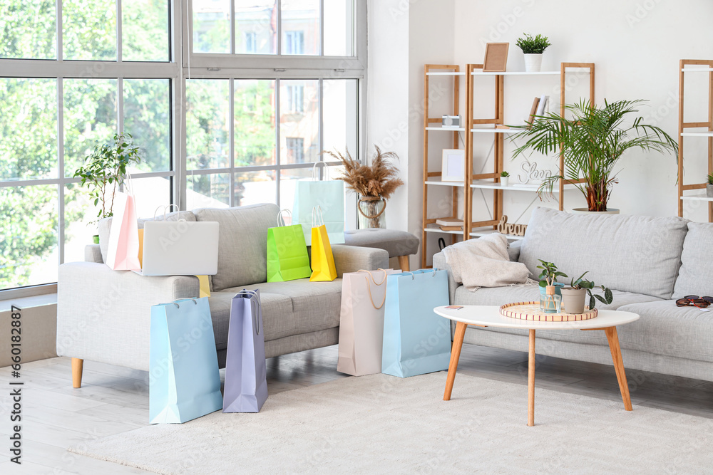 Laptop with shopping bags on sofa in living room