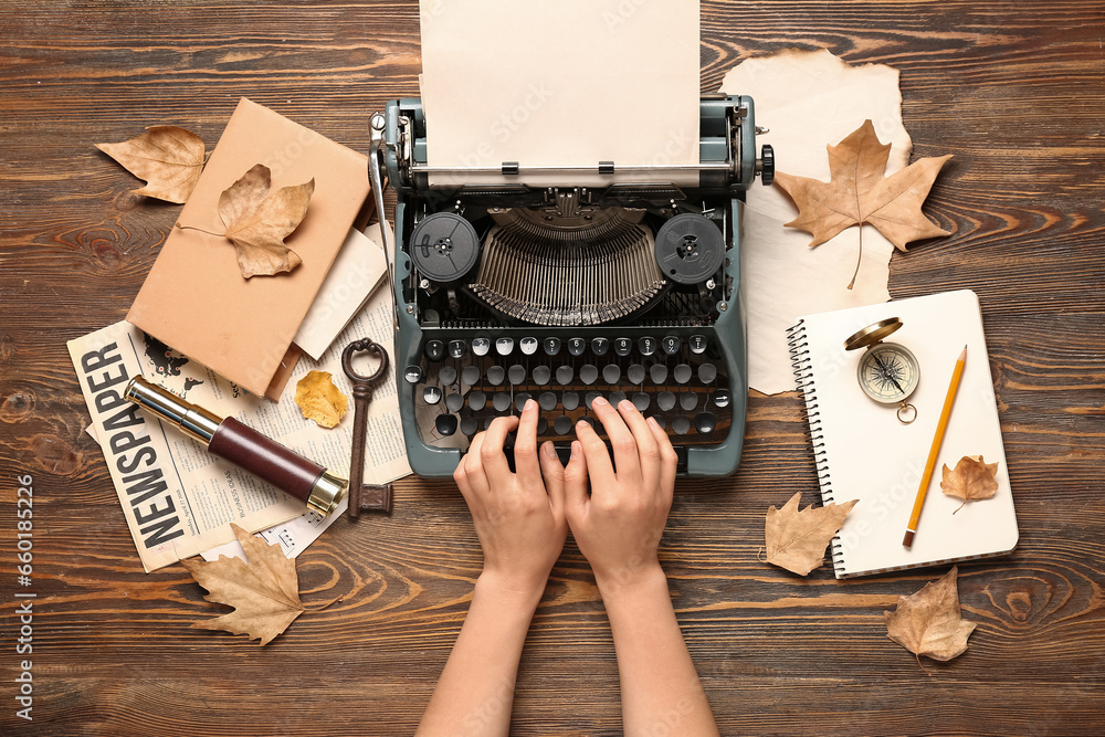 Woman using vintage typewriter on wooden background