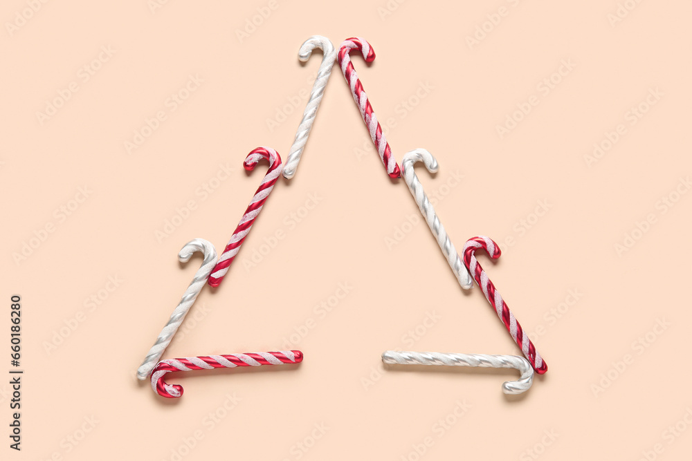 Christmas tree made of candy cane toys on beige background